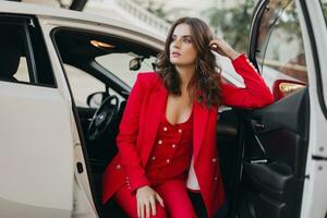 lindo sexy rico o negócio mulher dentro vermelho terno posando dentro branco carro foto