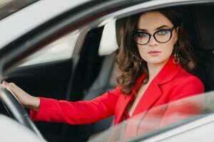 lindo sexy rico o negócio mulher dentro vermelho terno sentado dentro branco carro, vestindo óculos foto