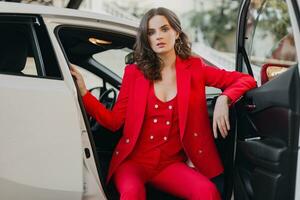 lindo sexy rico o negócio mulher dentro vermelho terno posando dentro branco carro foto