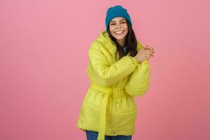 atraente ativo mulher posando em Rosa fundo dentro colorida inverno baixa Jaqueta do brilhante amarelo cor, sorridente diversão, caloroso casaco moda tendência, louco chocado surpreso face expressão foto