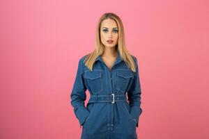 animado atraente menina posando em Rosa fundo dentro jeans No geral moda tendência foto