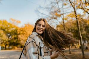 atraente jovem mulher caminhando dentro outono vestindo Jaqueta foto