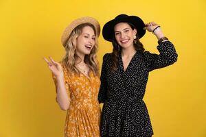 lindo mulheres amigos juntos isolado em amarelo fundo dentro Preto e amarelo vestir e chapéu foto