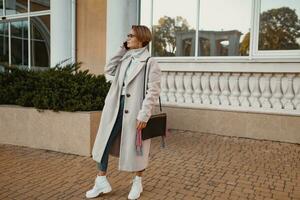 à moda elegante mulher caminhando dentro rua dentro elegante estilo casaco foto