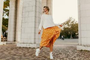 jovem bonita feliz sorridente mulher dentro amarelo impresso vestir e tricotado branco suéter foto