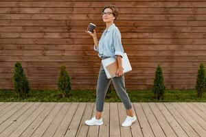 jovem bonita mulher sentado com computador portátil dentro moderno parque rua foto