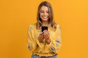 lindo atraente sorridente mulher dentro amarelo camisa segurando Smartphone foto