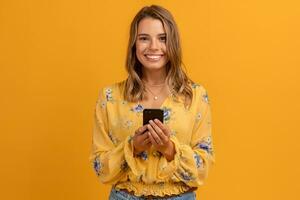 lindo atraente sorridente mulher dentro amarelo camisa segurando Smartphone foto