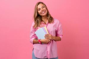 loiro bonita mulher dentro Rosa camisa sorridente segurando segurando cadernos foto