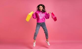 hispânico bonita mulher dentro Rosa moletom com capuz sorridente pulando foto