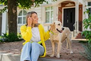 feliz sorridente mulher dentro amarelo suéter caminhando às dela casa com uma cachorro dourado retriever foto