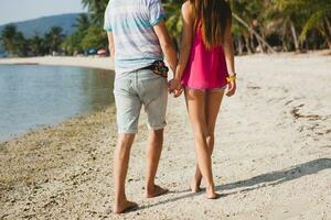 jovem lindo casal caminhando em tropical de praia foto