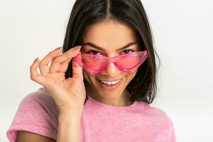 atraente mulher dentro Rosa camiseta e oculos de sol foto