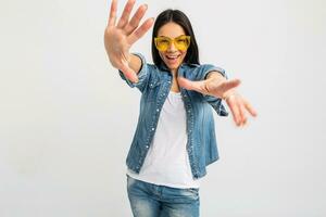 atraente mulher vestido jeans e jeans camisa vestindo amarelo oculos de sol foto