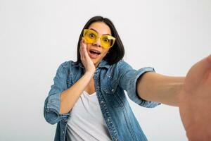 atraente mulher vestido jeans e jeans camisa vestindo amarelo oculos de sol foto