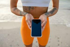 bonita jovem mulher fazendo Esportes dentro a manhã dentro à moda esporte equipamento roupa de esporte, segurando telefone foto