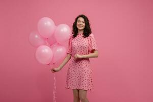 bonita jovem mulher posando isolado em Rosa estúdio fundo com Rosa ar balões foto