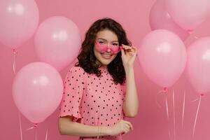 bonita jovem mulher posando isolado em Rosa estúdio fundo com Rosa ar balões foto