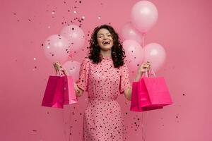 bonita jovem mulher em compras posando isolado em Rosa estúdio fundo com Rosa ar balões foto