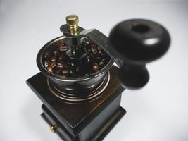 o moedor de café de madeira com grãos de café no fundo branco. o foco na alça foto
