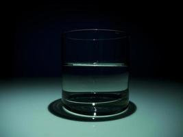 copo meio cheio com água no escuro. fundo preto foto
