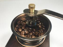 grãos de café no moedor de café de madeira em fundo branco. fechar-se foto