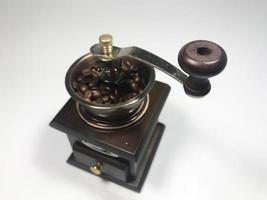 o moedor de café de madeira com grãos de café no fundo branco foto