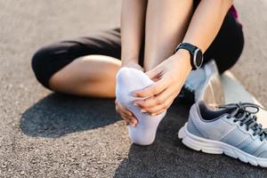 correndo lesão perna acidente-esporte mulher corredor machucando segurando doloroso tornozelo torcido com dor. atleta com dores nas articulações ou nos músculos e dificuldade para sentir dores na parte inferior do corpo. foto