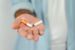 close up da mão do homem segurando o cigarro quebrado na mão. conceito de parar de fumar, mundo sem dia do tabaco. foto