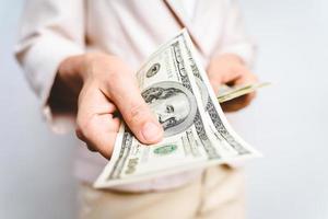 close up das mãos de mulher de negócios propondo dinheiro nos notas de dólar em fundo branco. conceito de dinheiro. foto