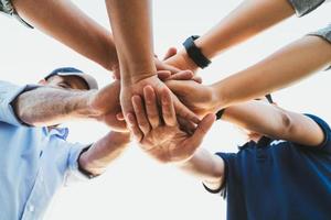 pessoas juntando as mãos. amigos com uma pilha de mãos, mostrando unidade e trabalho em equipe. conceito de equipe amizade felicidade lazer parceria. foto