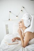 jovem mulher feliz lendo livro de papel na cama. foto