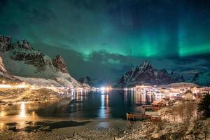 aurora boreal sobre a luz de uma vila escandinava brilhando no inverno foto