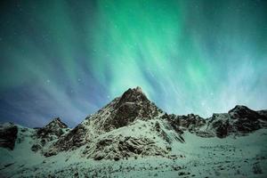 explosão de aurora boreal na montanha de neve foto