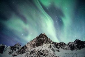 monte nevado com aurora boreal dançando com estrela cadente foto