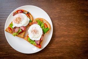 pão integral torrado com vegetais, bacon e ovo ou ovo benedict, no café da manhã foto