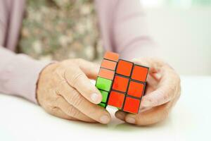 Bangkok, Tailândia - pode 15, 2022 ásia idosos mulher jogando rubik cubo jogos para prática cérebro Treinamento para Socorro demência prevenção e alzheimer doença. foto