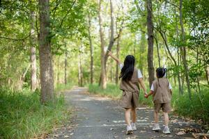 ásia pequeno meninas explorar natureza através ampliação óculos e binóculos dentro a parque. Educação, campo viagens, pesquisar, e descoberta conceitos. foto