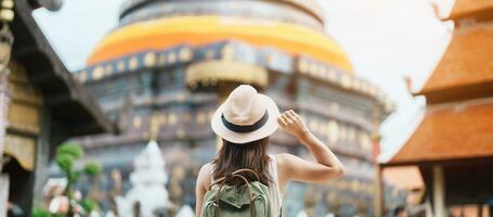 jovem ásia mulher viajante dentro branco vestir com chapéu e saco viajando dentro wat phra este Lampang luang, turista Visita às lampang, tailândia.. Ásia viagem, período de férias e verão feriado conceito foto