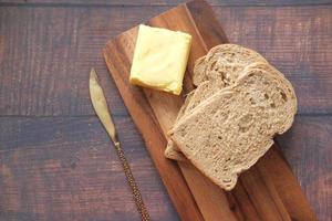 fatia de manteiga e pão integral na tábua de cortar