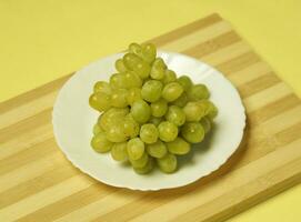 uma prato do uvas em uma de madeira borda foto