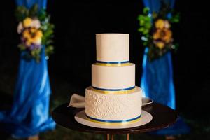 bolo de casamento em um banco de madeira contra um fundo de cachoeira foto