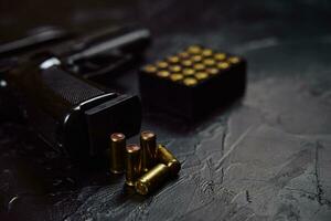 pistola com cartuchos na mesa de concreto preto. foto