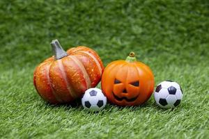 bola de futebol para o dia de halloween com abóbora na grama verde foto