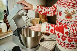 mulher cozinhando às casa cozinha, usar elétrico misturador para preparando massa foto