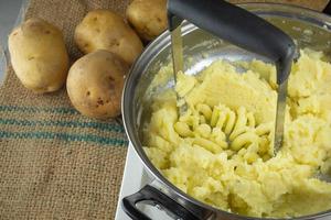 esmagar batatas cozidas com um espremedor de batatas caseiro foto