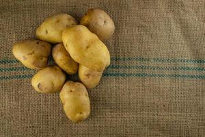 Batatas cruas para cozinhar em esteiras de sacos. foto