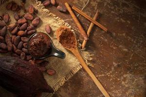 grãos de cacau e nibs de cacau dispostos em fundo de madeira rústico foto