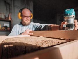 carpinteiro barbudo trabalhando com um fraser elétrico