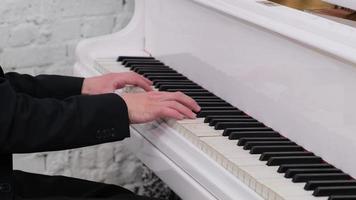 uma foto de mãos masculinas tocando o piano de cauda branco brilhante